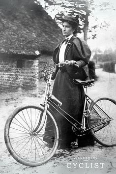 an old black and white photo of a woman standing next to a bicycle