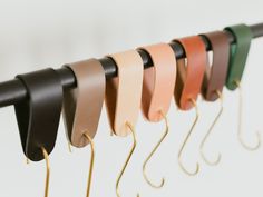 a row of different colored leathers hanging from hooks