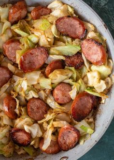 sausage and cabbage in a skillet with a wooden spoon