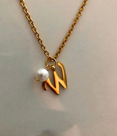 Letter W necklace, set on a stainless steel ,golden color chain. Chain length 19'  With addition cost there is an option to add a white freshwater pearl, as a charm, next to the letter. 6 mm, white round pearl Kindly choose your option. Beautiful spiritual gift. Please make sure you to pay attention to the size of the pendant. I have added pictures next to 25 cent coin, and measurement tape.  Need a different length just write it to me in the "message to the seller" box of the order form. **LIMI Initial Necklace With Pearl Pendant For Gift, Initial Pendant Necklace With Pearl For Gift, Pearl Pendant Initial Necklace As Gift, Elegant Initials Necklace In Stainless Steel, Elegant Initials Stainless Steel Necklace, Elegant Stainless Steel Initial Pendant Necklace, Elegant Stainless Steel Initials Necklace, Personalized White Stainless Steel Charm Necklace, Elegant Initials Name Necklace