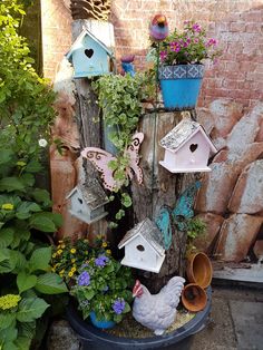 several birdhouses and flowers in a pot on the side of a building with a brick wall behind them