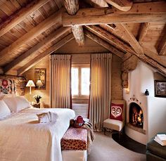 a large bed sitting under a wooden ceiling next to a fire place in a bedroom