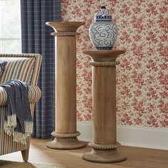 two vases sitting next to each other in front of a wallpapered room