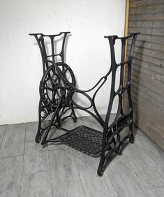 two black metal racks with wheels on them sitting next to a wooden wall and floor