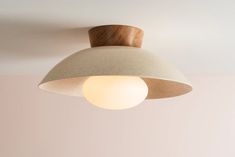 a light that is hanging from the ceiling with a wooden object on it's side