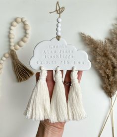 a person holding up a white cloud with tassels on it and the words clouds are