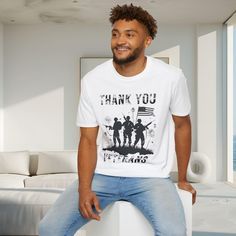 a man sitting on top of a white pillar wearing a t - shirt that says thank you veterans