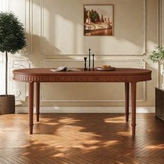 a wooden table sitting on top of a hard wood floor next to a potted plant