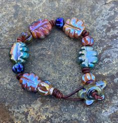 a beaded bracelet with glass beads and leather cord on a rock, close up