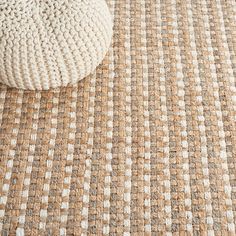 a white knitted bag sitting on top of a brown and white carpeted floor