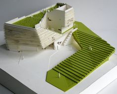 an architectural model of a building with green grass on the roof and in the ground