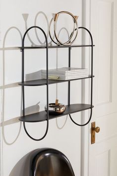 a metal shelf with books on it in front of a white door and a black chair