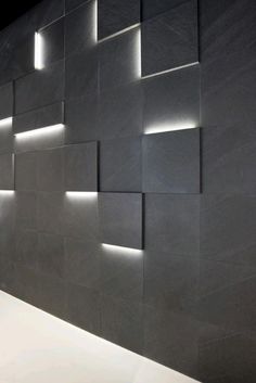 a wall with some lights on it next to a sink and counter in a room