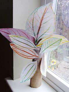 a vase filled with leaves sitting on top of a window sill