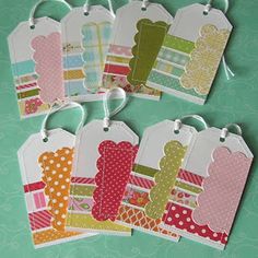 four tags with different designs on them sitting on top of a green surface, one has a ribbon and the other has polka dots