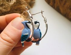 small blue bird sitting on top of a hoop earrings