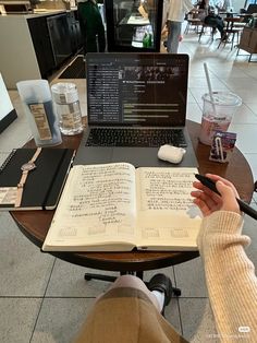 a person sitting at a table with a laptop and open book in front of them