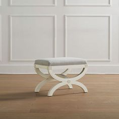 a white bench sitting on top of a hard wood floor in front of a wall