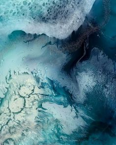 an aerial view of the ocean with blue and white waves crashing on it's surface