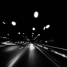 black and white photograph of an empty highway at night