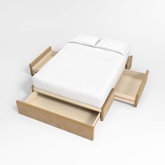 a bed sitting on top of a wooden platform next to a white pillow and blanket