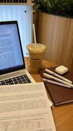 an open laptop computer sitting on top of a wooden table next to a cup of coffee