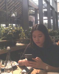 a woman sitting at a table looking at her cell phone