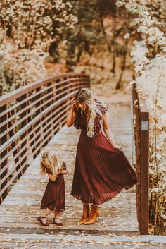 a mother and daughter walking across a bridge