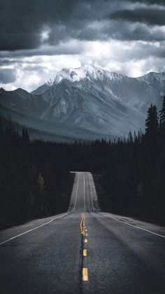 an empty road with trees and mountains in the background that has a smiley face drawn on it