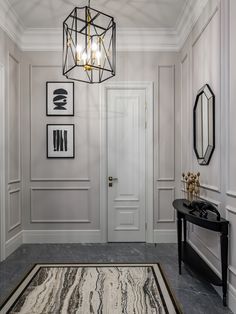 a foyer with white walls and black accents, an area rug on the floor and two framed pictures above it