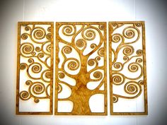 three wooden wall art pieces with swirly tree designs on the front and back of each piece