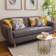 a living room with grey couches and yellow throw pillows on top of the rug