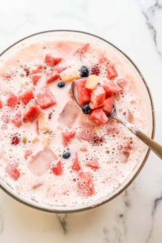 watermelon, blueberries and other fruits are in a bowl with a spoon