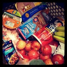 a basket full of food including apples, bananas and yogurt is seen in this image