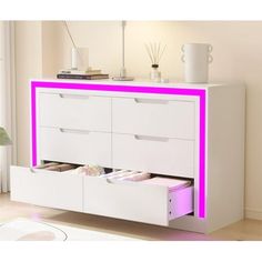 a white dresser with drawers and pink lights