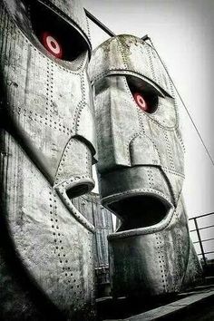 a large metal mask with red eyes on top of a building