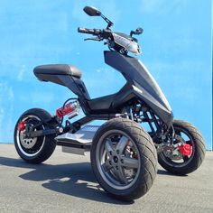 an electric trike parked in front of a blue wall with the words sale on it