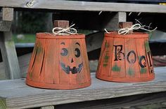 two orange lampshades with faces painted on them sitting on a wooden bench outside