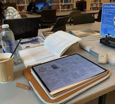 a tablet computer sitting on top of a table next to a cup of coffee and books