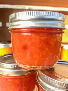 three jars filled with jam sitting on top of each other in front of some containers