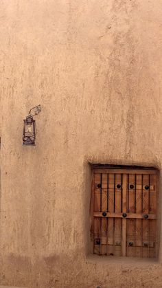 two windows on the side of a building with bars in them and a bird perched on top of one window