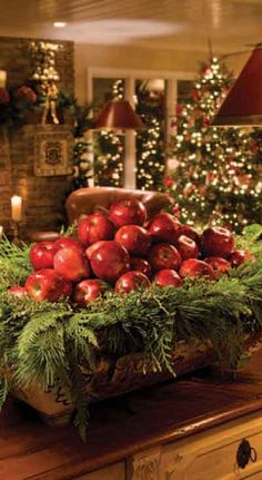 an image of christmas decorations in the living room with red apples and pine cones on display