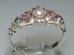 "This stunning Georgian Inspired Trilogy design is made to order and handset with a centre cultured freshwater pearl measuring 4.25mm (0.17\") and two round cut natural Pink Tourmaline gemstones measuring 3.5mm (0.14\").   The gemstones are natural, earth-mined and ethically sourced Your ring will be fully tested and hallmarked by the London or Birmingham Assay Office giving you the assurance of a high quality piece to wear and treasure FOR UK, AUSTRALIAN, EUROPEAN & NON-US BUYERS :  If you know Trilogy Ring, Silver Pearls