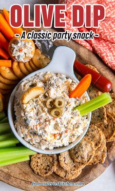 a plate with crackers, carrots, celery and olive dip