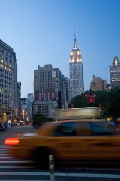 a blurry image of a city street with cars and buildings in the background at dusk