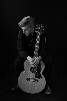 a man sitting on the ground with his guitar in front of him, black and white photo