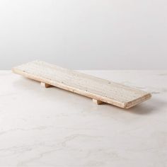 a white marble table top with a wooden board on one end and two legs in the other