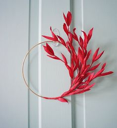 a red plant is hanging on the side of a white wall with a gold hoop