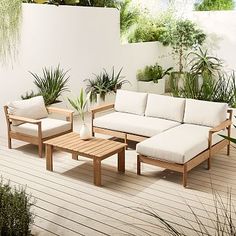 a couch and table on a deck with potted plants