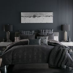 a bedroom with black walls and grey bedding